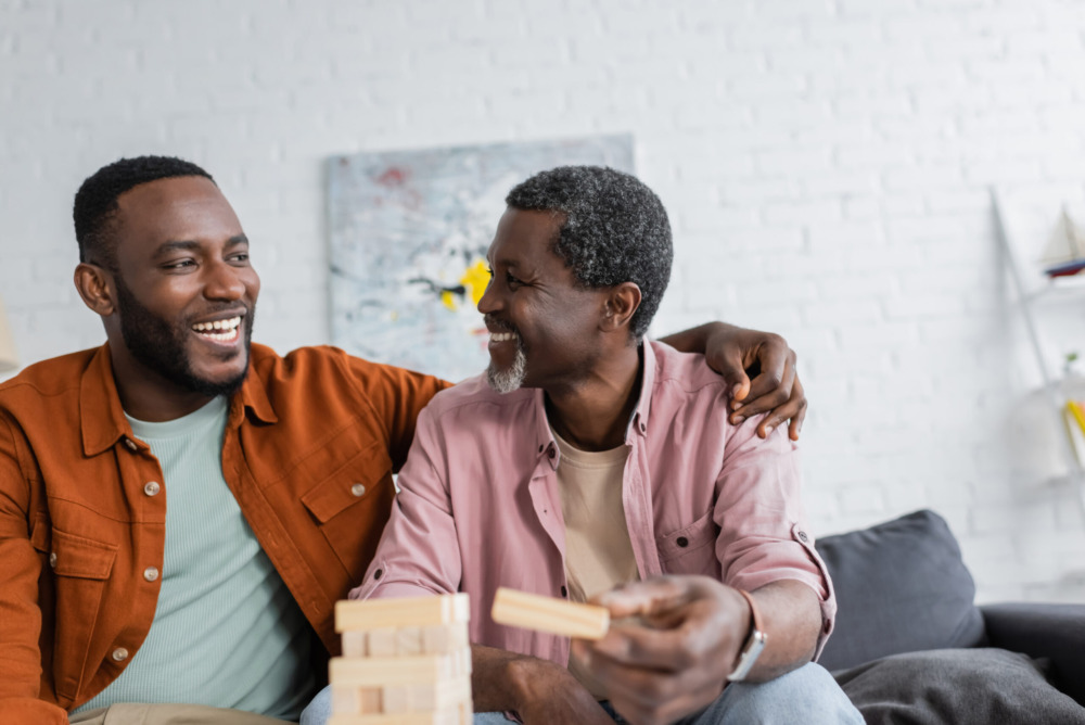 Mature dad and son smiling while playing a game