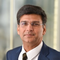 Brunette man wearing glassed and navy suit smiling for professional headshot