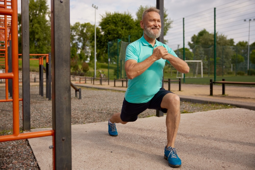 Senior man performing a lunge exercise outside in the park