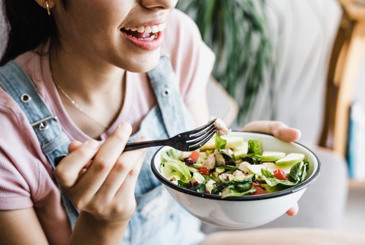 Young woman eats dark leafy greens to boost health and reduce inflammation