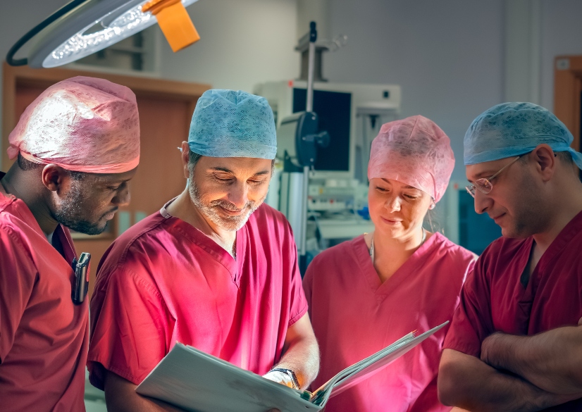 Three male and one female surgeon wearing pink scrubs