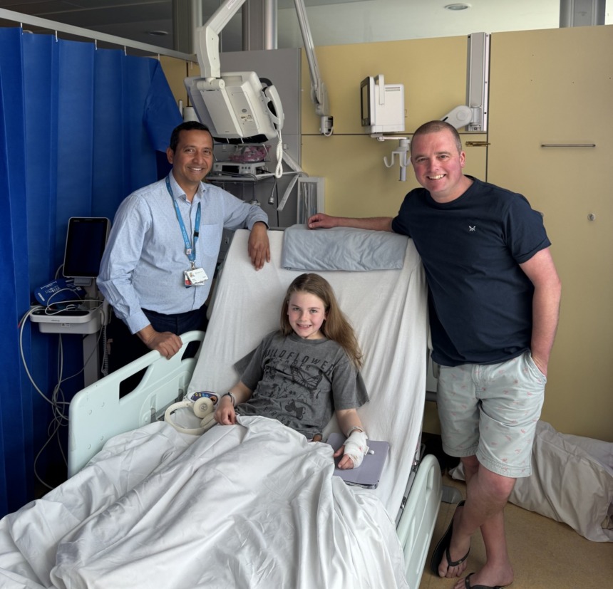 9 year old girl in hospital bed with her father and surgeon standing nearby